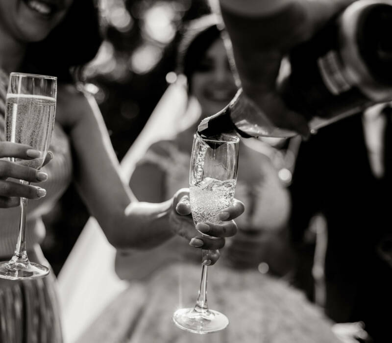 Monochrome view of a pouring bottle into glasses and champagne Monochrome view of a pouring bottle into glasses and champagne glasses in tender women's hands